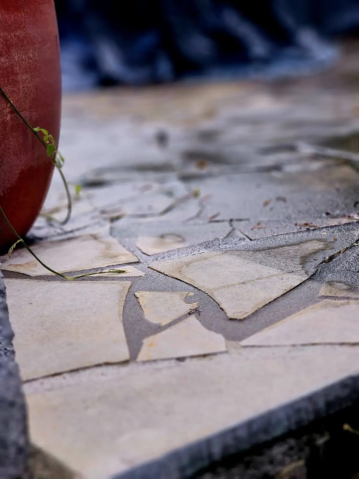 Nahaufnahme einer Betonsteinfläche mit dunklen, fleckigen Verfärbungen im Material.