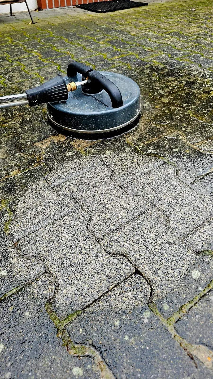 Flächenreiniger auf einer Pflasterfläche, links der bereits bearbeitete Bereich, rechts der ursprüngliche Zustand.