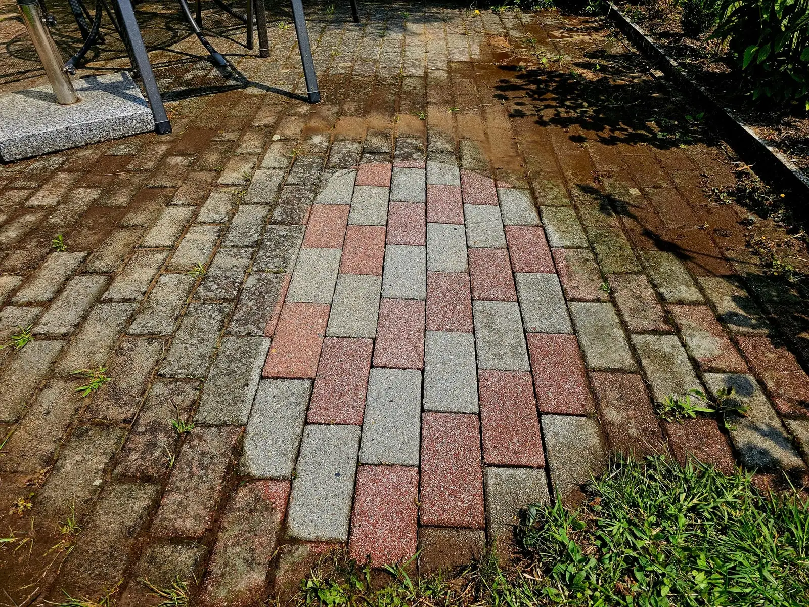 Natursteinweg in Potsdam während der Reinigung, nasse Oberfläche mit sichtbarer Bearbeitungsgrenze.